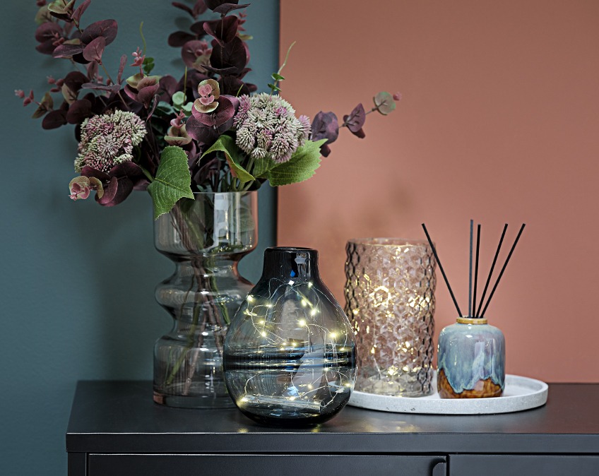 Vases with light strings and flowers on a table 