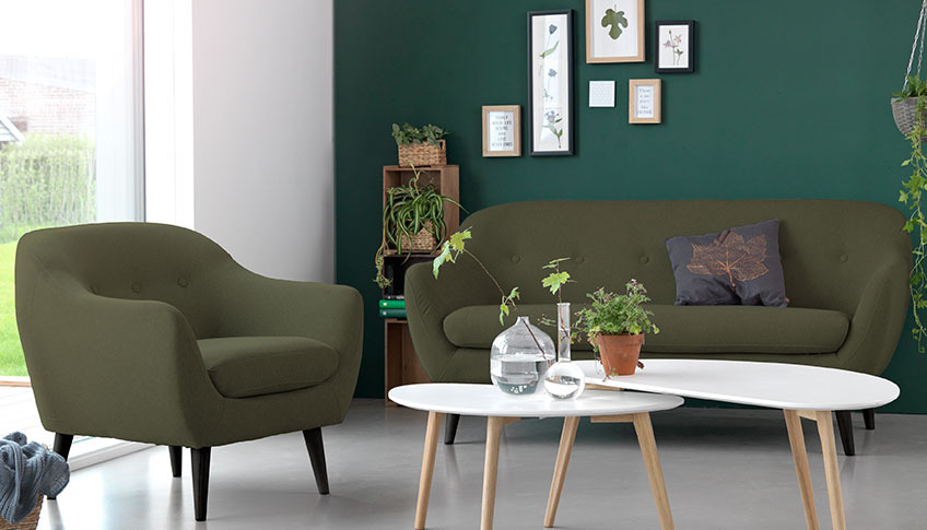 A living room with a green velvet sofa and armchair a two coffee tables