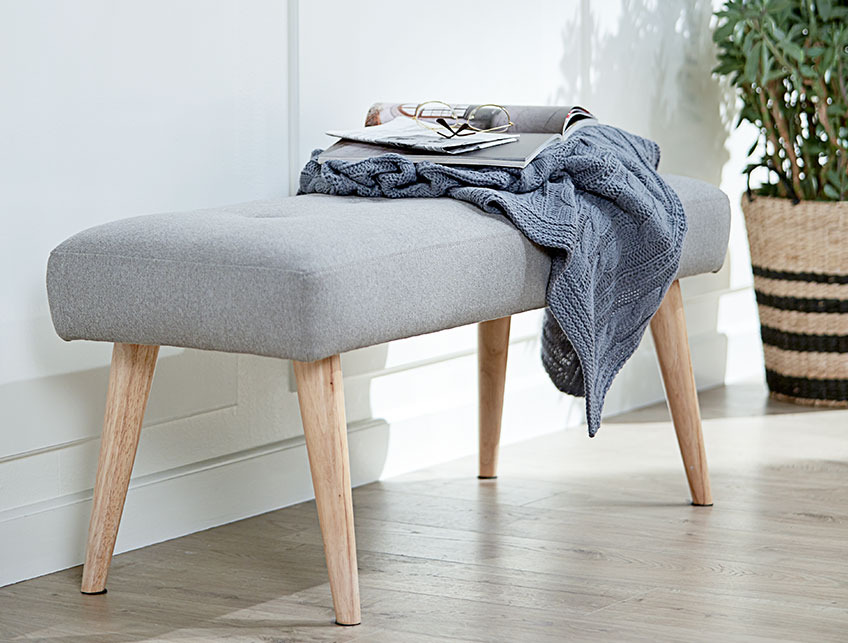 A grey bench with wooden legs in a hall