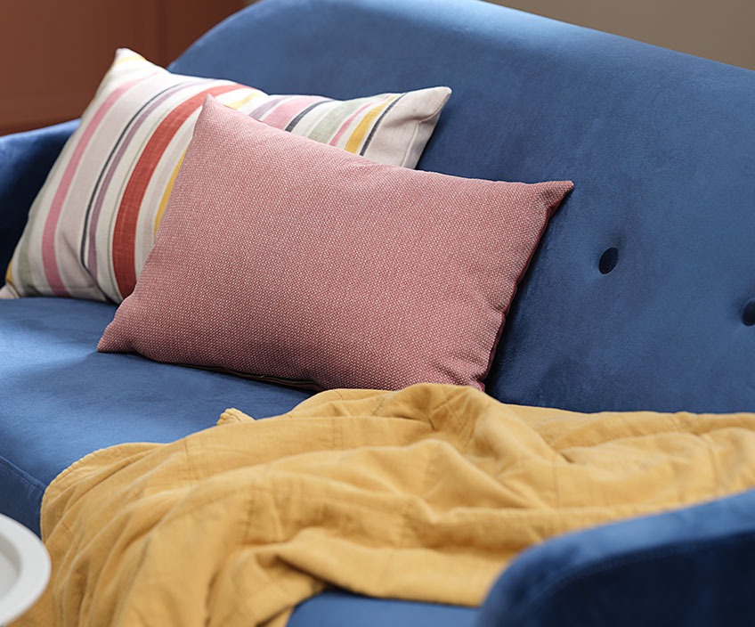 Striped KAPRIFOL cushion, rose LIJLE cushion and quilted VALMUE blanket in the blue EGEDAL sofa Colourful cushions and a quilted blanket in a blue sofa