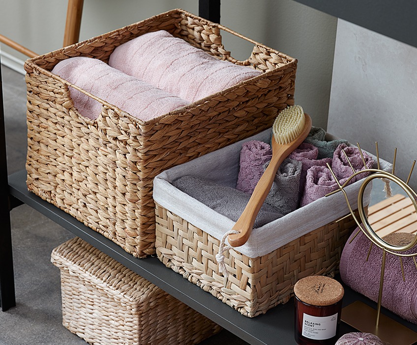 Nicely folded towels in wicker storage baskets on a shelf 