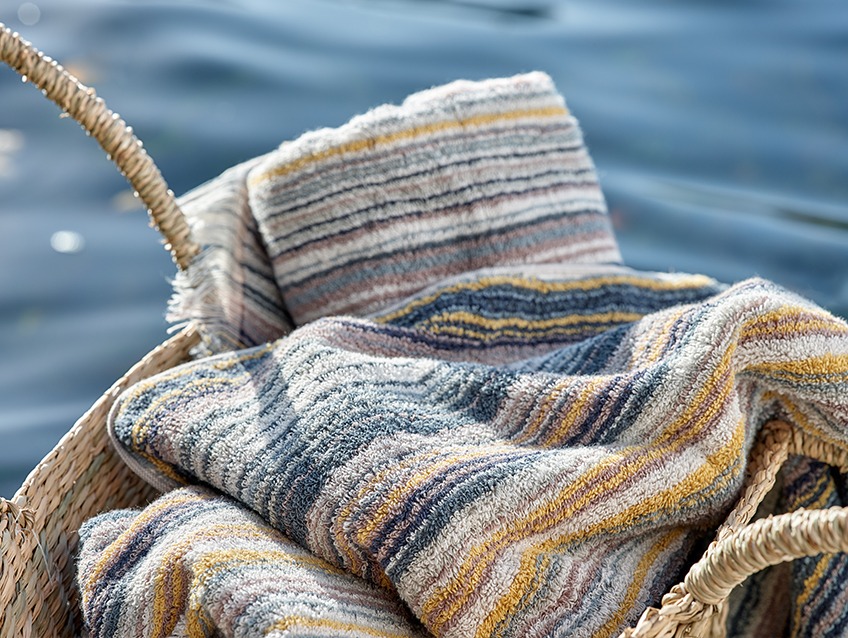 Wicker basket with striped towels by a lake