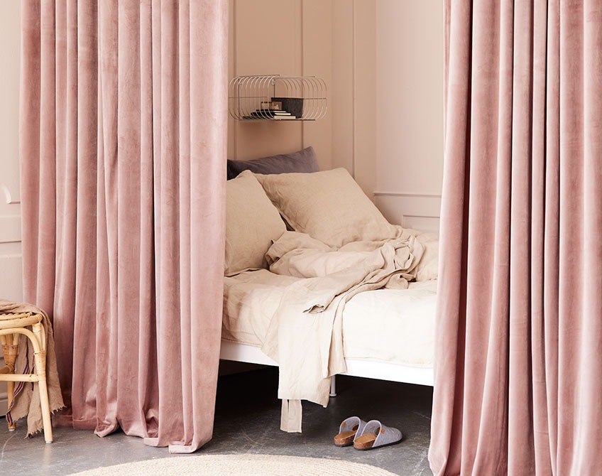 Rose coloured curtains used to separate a sleeping area from a large living room 