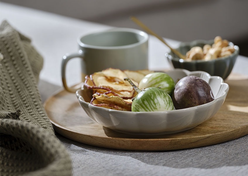 Wooden tray with grey bowl filled with fruits placed on sofa