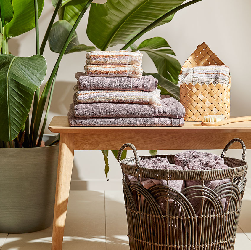 NORA and SEGERSTA towels, OPE basket on the bench and STEINN basket with towels on the floor Cotton towels and a wicker basket on a bench in a bathroom