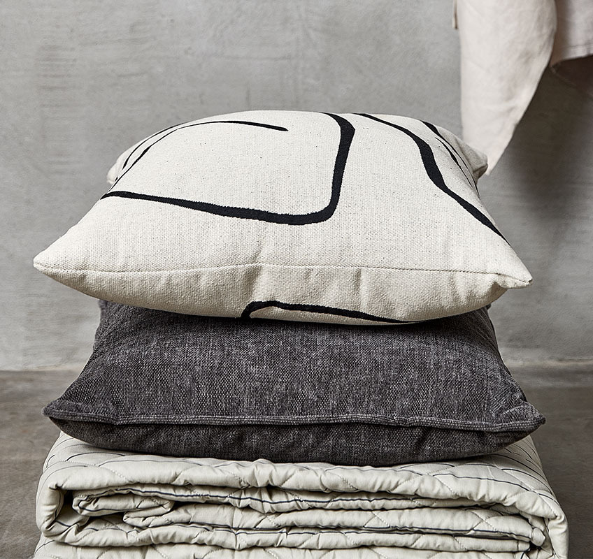 Quilted blanket and two cushions in white, beige, and grey colours