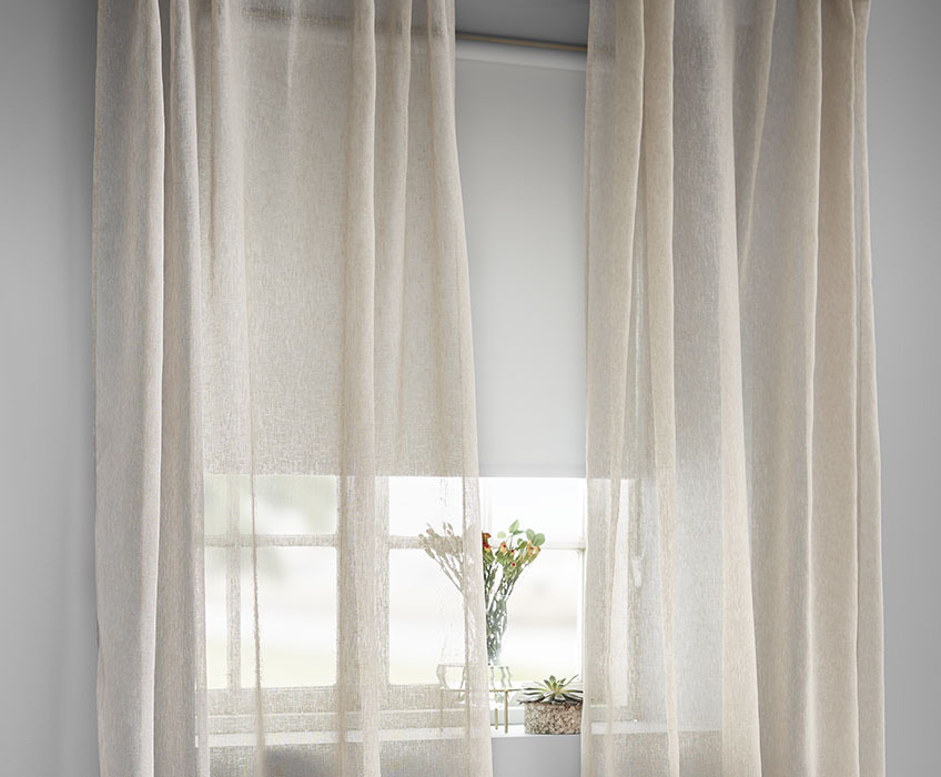 White blackout roller blinds and sheer beige curtains