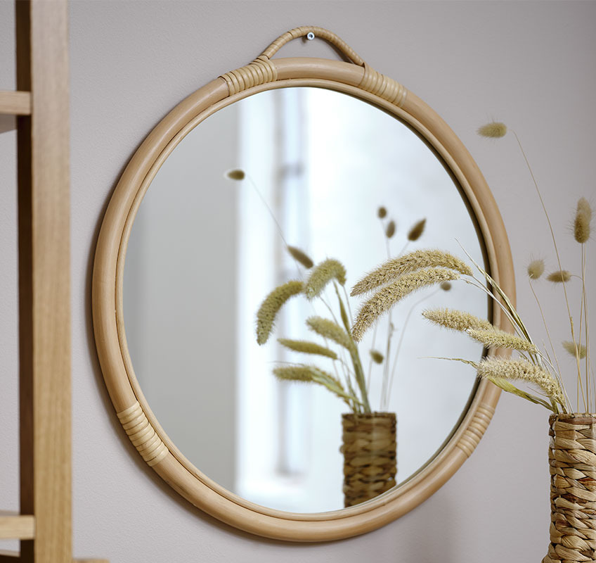 Round rattan mirror on beige wall 